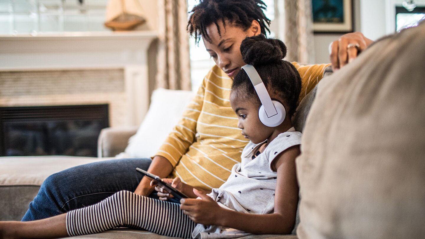Mother and daughter on couch using tablet