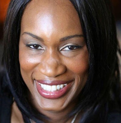 A Black woman with long, black hair smiles at the camera
