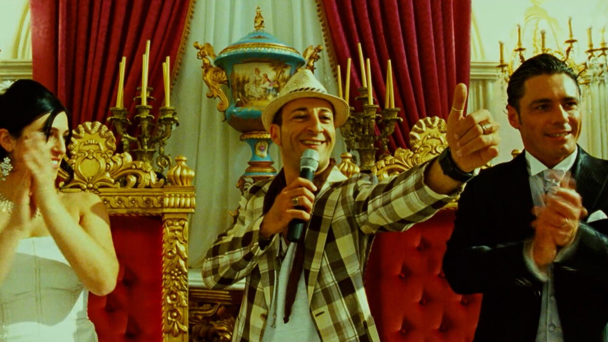 A man holding a mic directs a thumbs up.