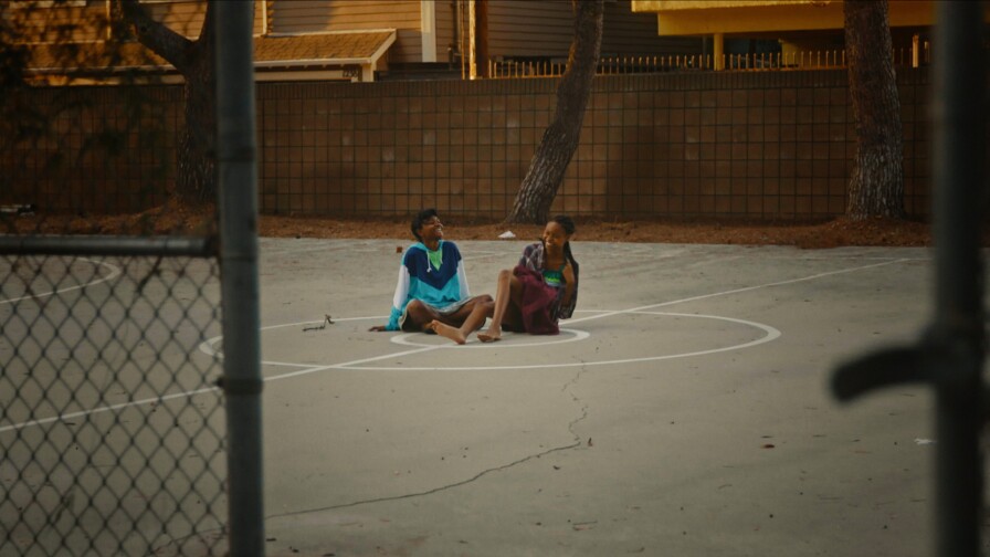 Two African American young girls talk at a basketball court in a still from "The Dope Years" | Fine Cut S21 Episode 1 still "California Then and Now"