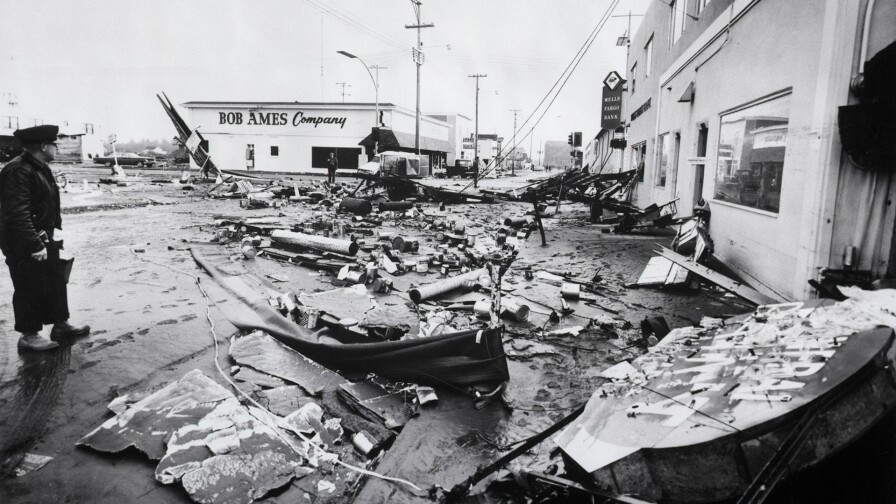 3/28/1964-Crescent City, CA- Unidentified man (l) stands amid debris-ridden city where martial law was declared after tremendous tidal waves from the Anchorage, Alaska earthquake destroyed 150 businesses and killed at least nine persons. Twelve-foot tidal