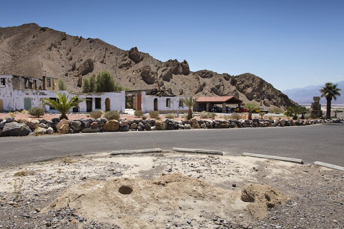 Grinding Rock, an ancient Timbisha mesquite grinding site pictured in the foreground at Furnace Creek Inn's lower parking lot. In recent years part of the remaining rock artifact washed away during a flash flood.