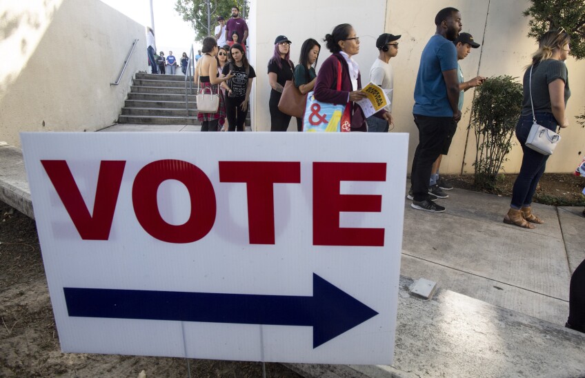 Vote Sign in front of a line of voters in Orange County for the midterm elections in November 2018