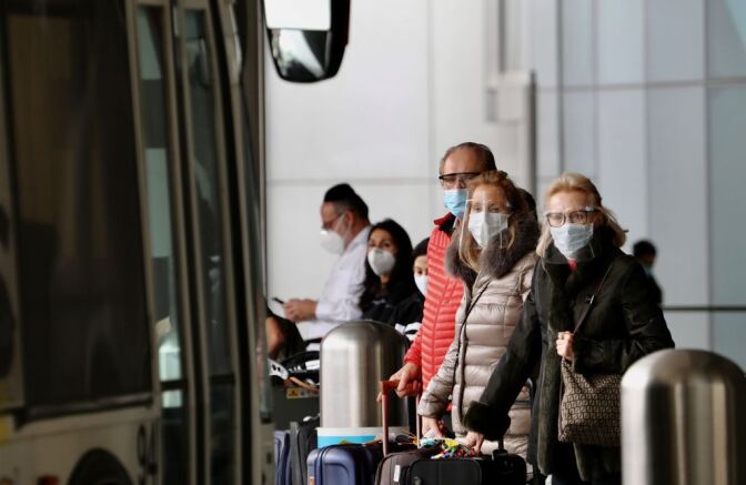 Travelers with face masks wait for public transportation services at the International Airport in Los Angeles, California, on Feb. 1, 2021.