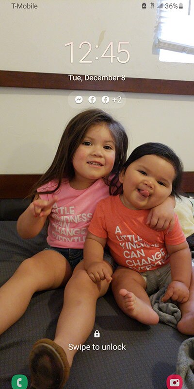 A little girl smiles as she holds her arm around a younger boy.