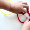 Closeup of a small child's hands as they shape craft pipe cleaners into different shapes like triangles and circles.