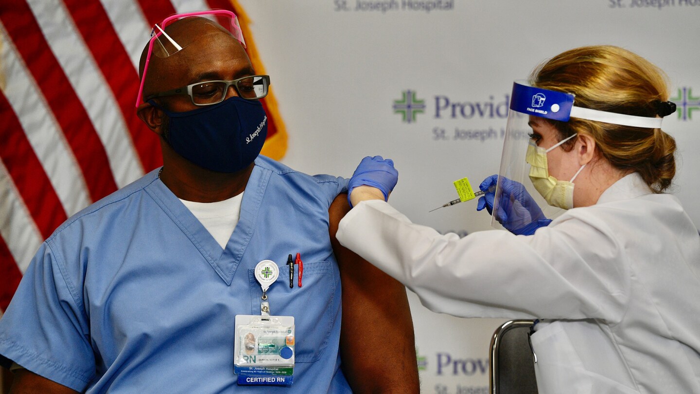 Nurse Michael Lowman gets the first dose of the Pfizer BioNTech COVID-19 vaccine from nurse practitioner Christie Aiello at Providence St. Joseph Hospital in Orange, CA, on Dec. 16, 2020. | Jeff Gritchen/MediaNews Group/Orange County Register via Getty
