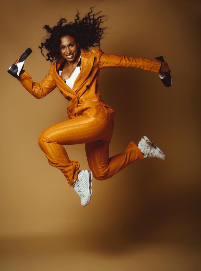 Chloe Arnold in flight wearing a suit and sneakers.