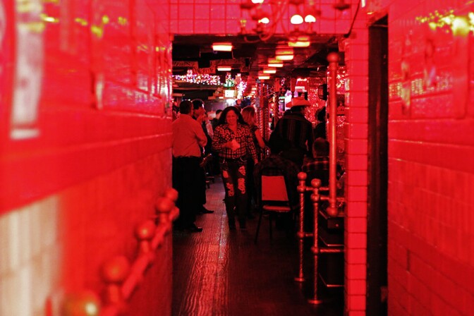 A woman walks toward a hallway under red lights.