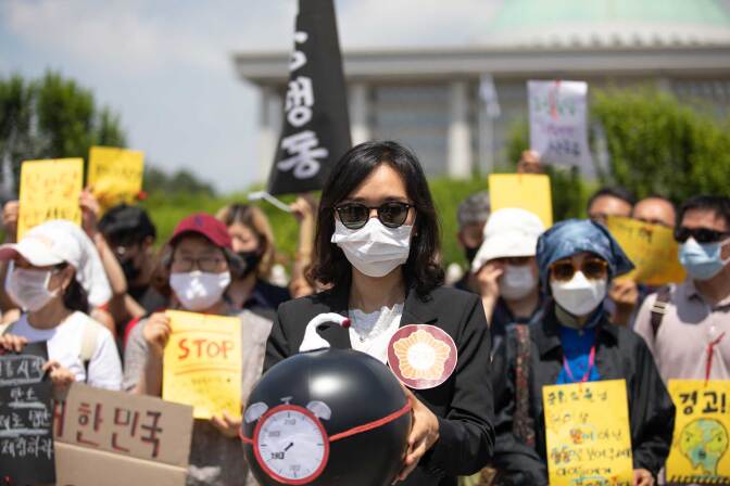 A demonstrator in Seoul, South Korea holds a time bomb symbolizing the climate crisis in June 2020. Demonstrators wear masks to protect themselves from the COVID-19 pandemic. | Chris Jung/NurPhoto via Getty Images