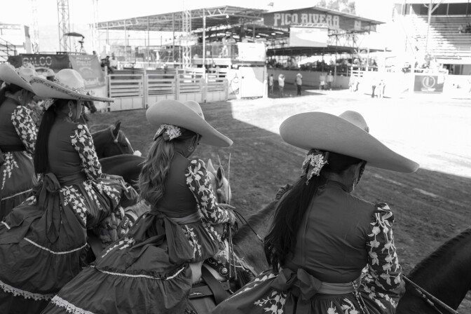 Mujeres con sombreros de ala ancha y un elaborado atuendo tradicional de rancho mexicano se sientan encima de los caballos.