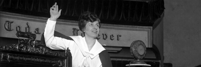 Aimee Semple McPherson preaching in front of a microphone (cropped for header)