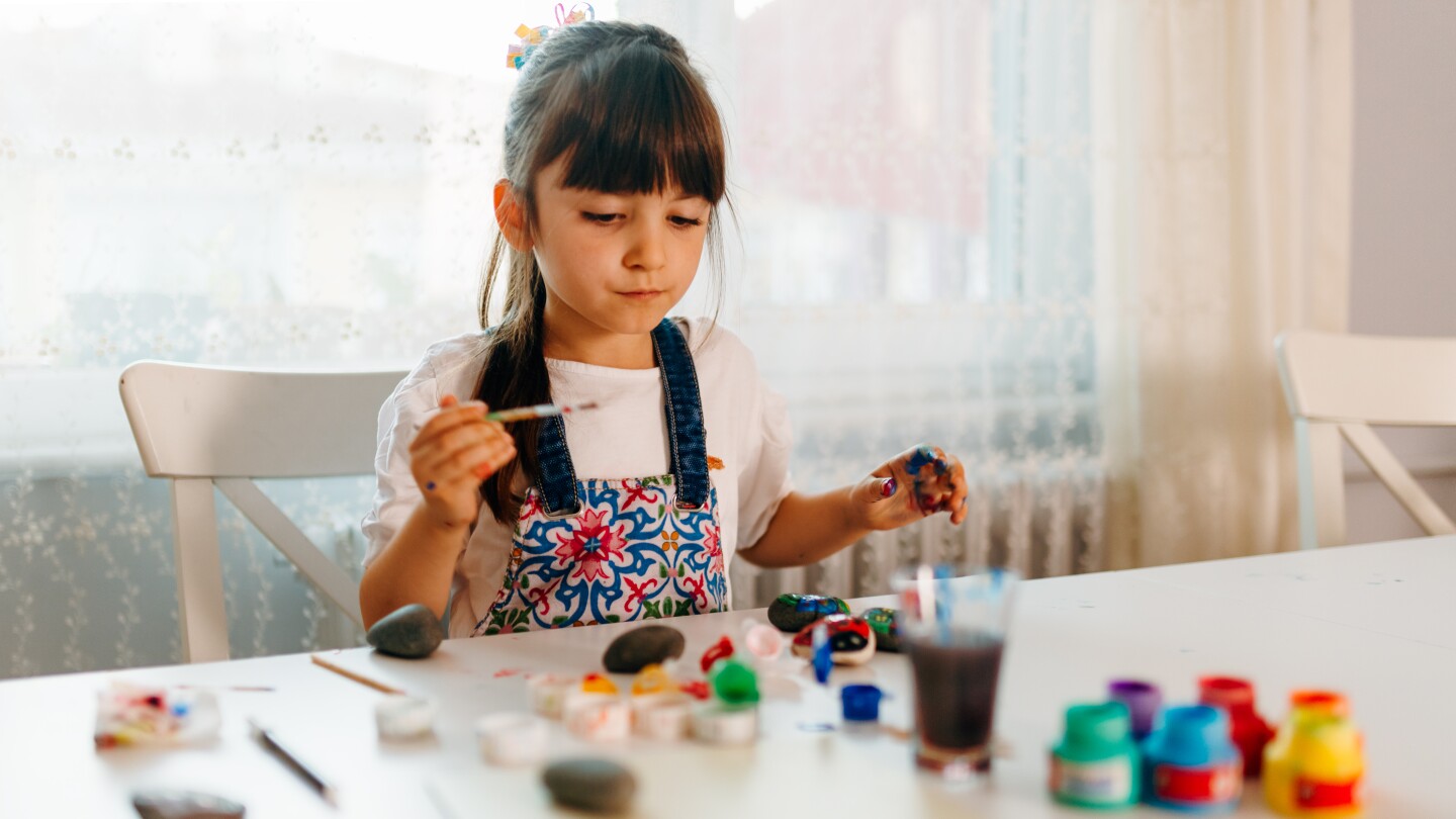 little girl is doing pattern rocks family math activity at home