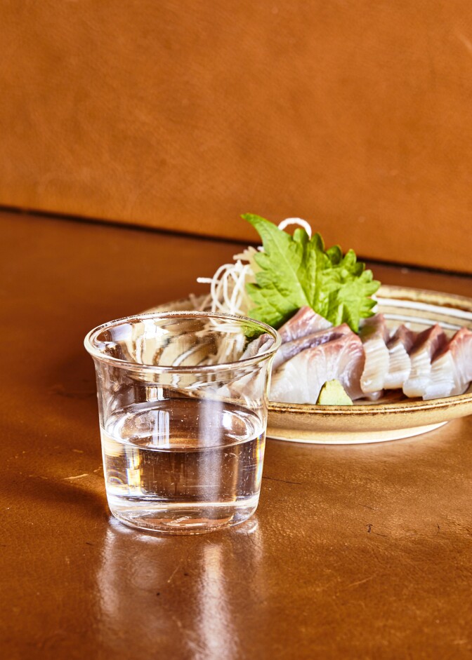 A cup of ginjo sake paired with a plate of kanpachi sashimi from Tsubaki.