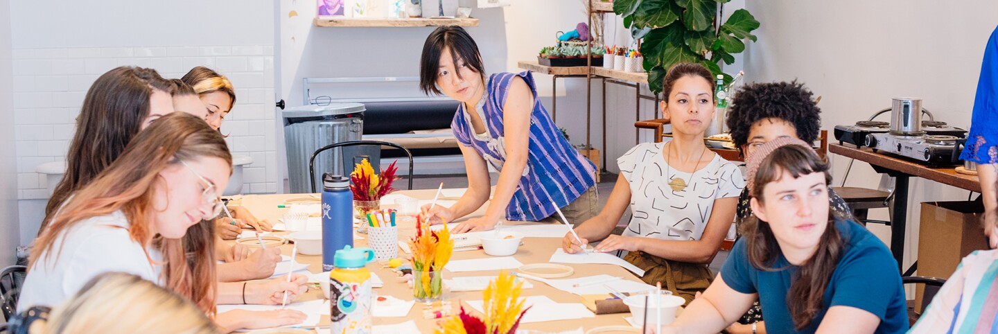 Women around a desk filled with craft objects | Courtesy of Makers Mess
