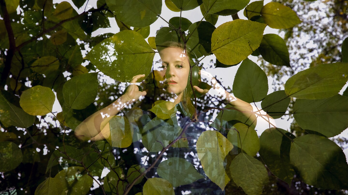 A woman wearing headphones overlaid with leaves