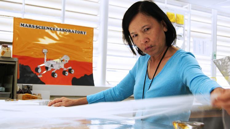Lien Pham pulling material for a thermal blanket in JPL's shield shop. | NASA/JPL-Caltech