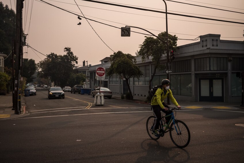 a man rides his bike across an intersection and the air in hazy