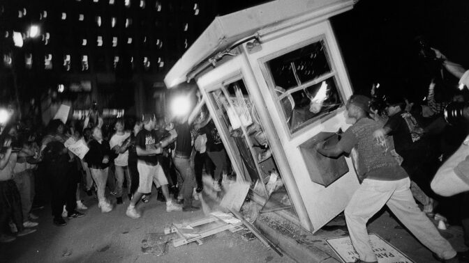 Rioters overturn a parking attendant booth at the LAPD Parker Center in downtown Los Angeles during the 1992 riots. | Ted Soqui/Corbis via Getty Images