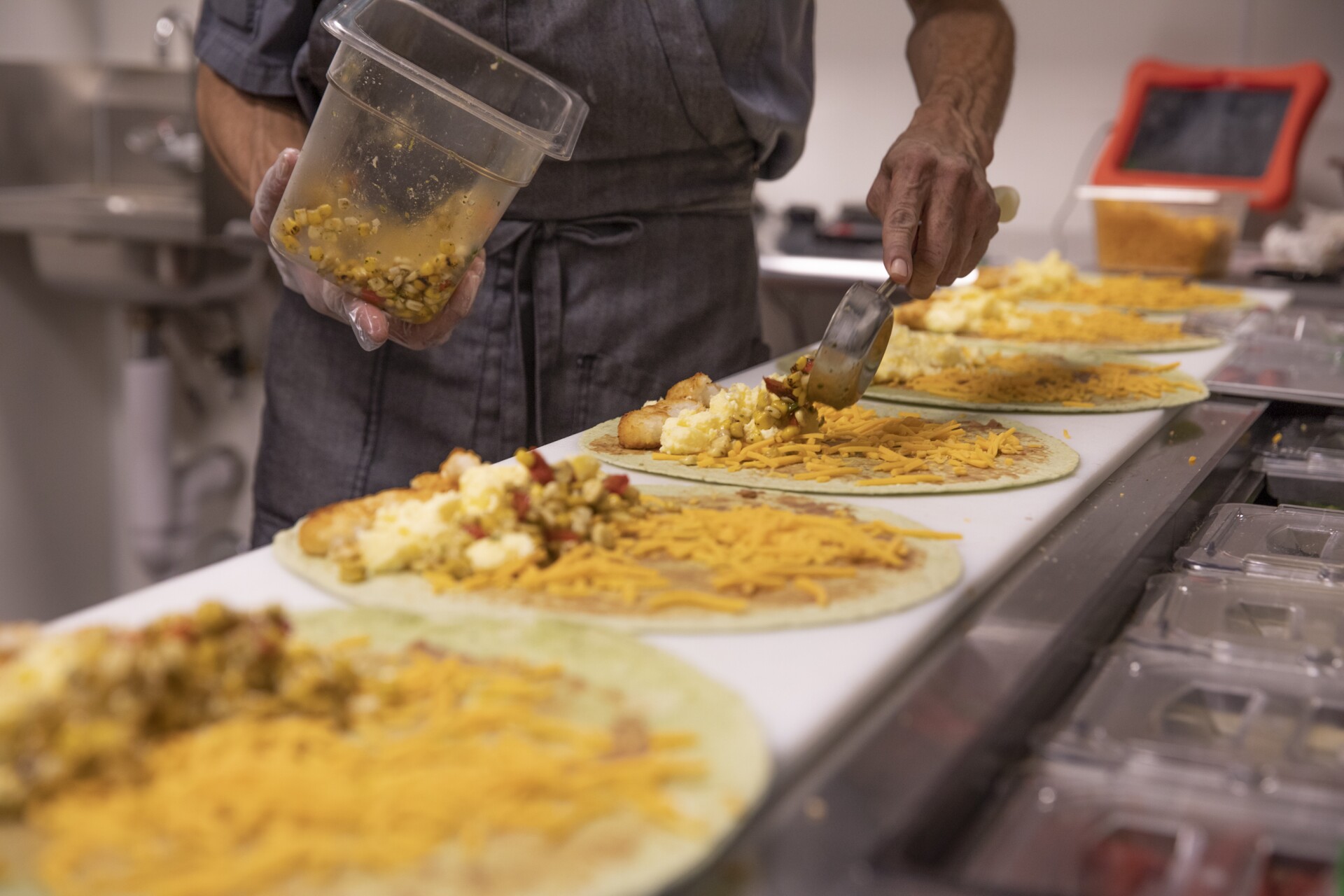 A man places toppings in a wrap.