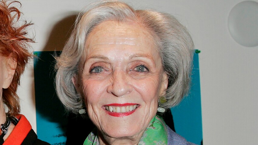 Shirley Baskin Familian smiles at the camera, wearing red lipstick and a green collar