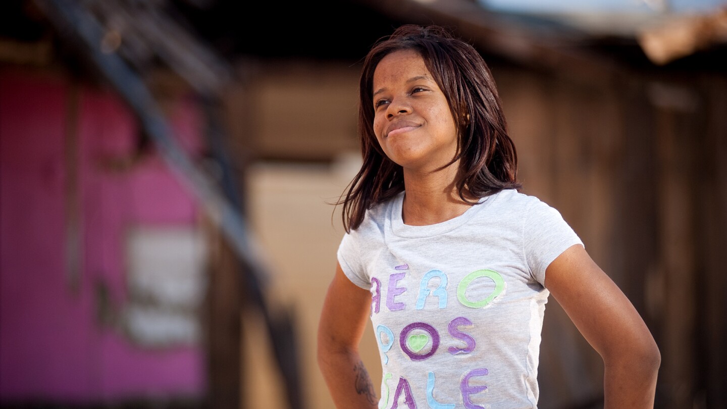 A young girl poses as she looks on with a content smile.