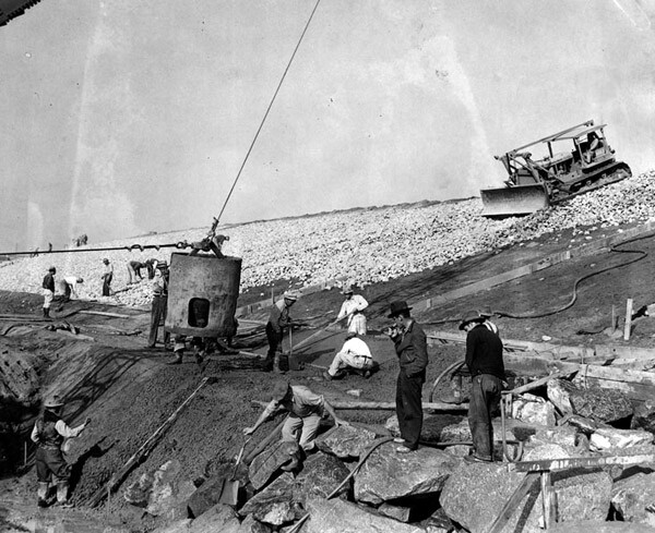 A large bucket of cement being dumped over the rocks on the river bank. Thousands of men have been working 24 hours a day in three shifts to complete the project at Verdugo Wash, 1938. Courtesy of the Los Angeles Public Library.