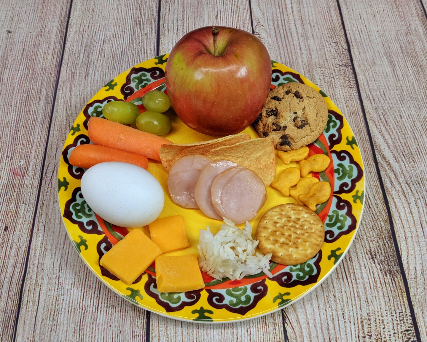 Snack items like small crackers, apple slices and cheese squares are arranged on a plate