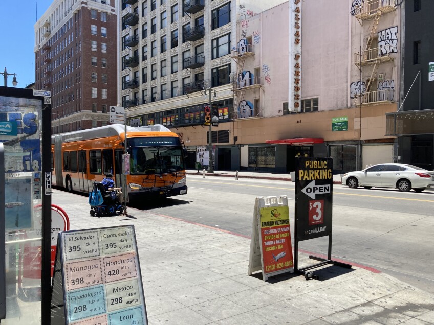 An L.A. Metro bus pulls up to a bus stop in Downtown L.A. as a transit rider prepares to board