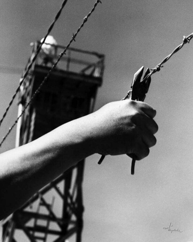 A hand cutting the barbed wire at Manzanar