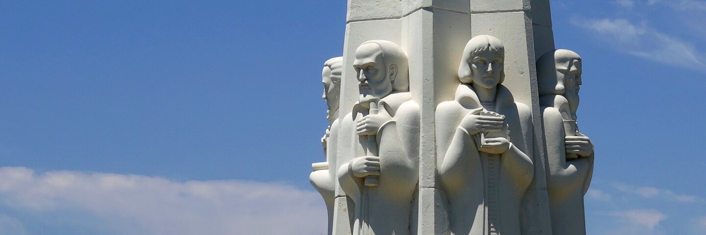 A monument that depicts some astronomers in the foreground with the Hollywood sign in the background.