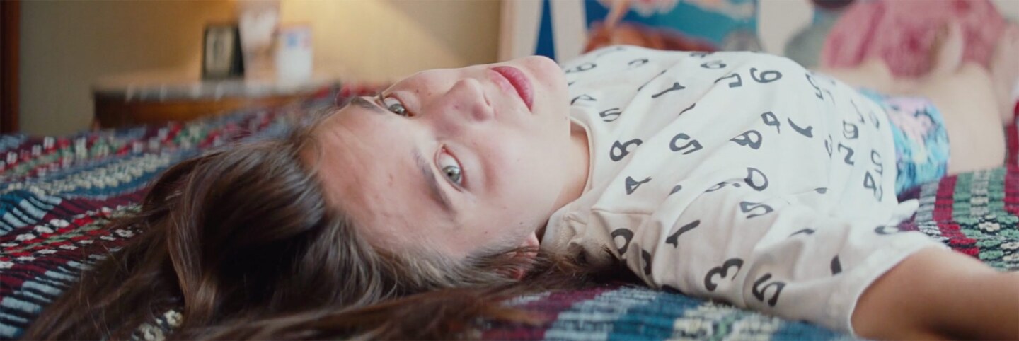 Still from Creme Caramel: A woman lies on her back on a bed.