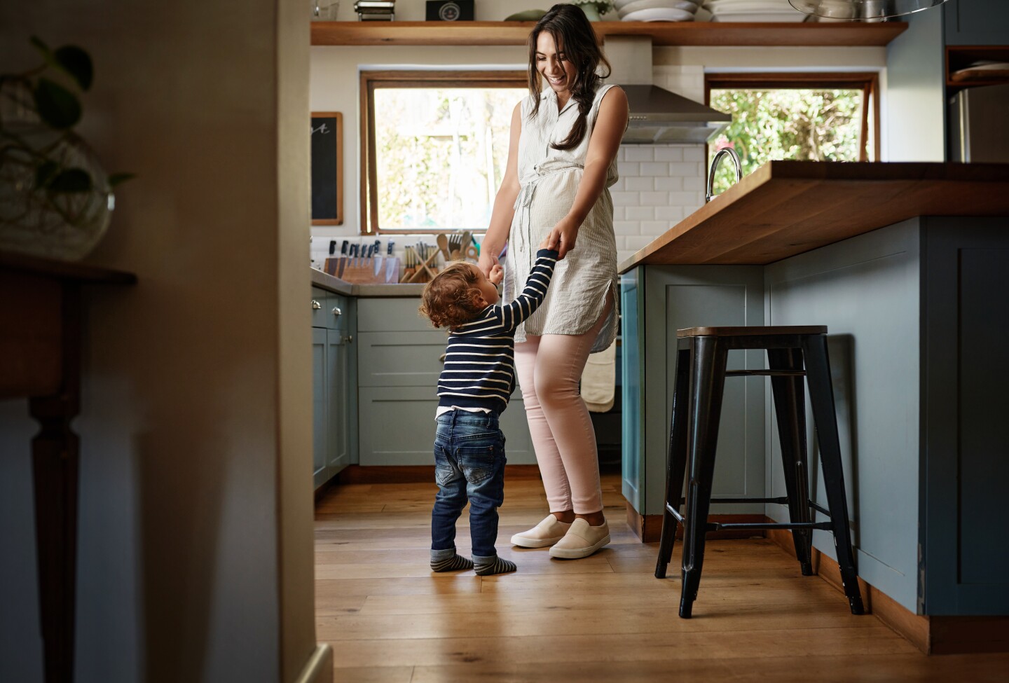 A mother and small daughter clean up toys while kneeling on the floor.