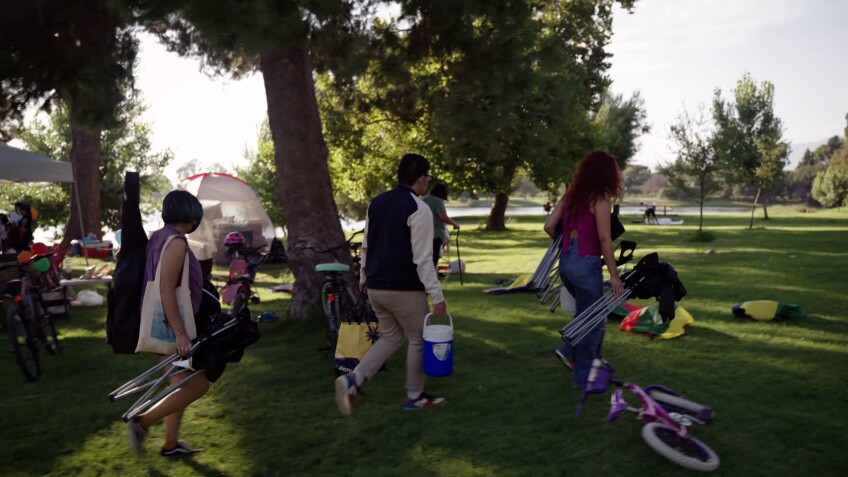 A family carries chairs and supplies for a day at the Whitter Narrows Recreation Area in South El Monte, California