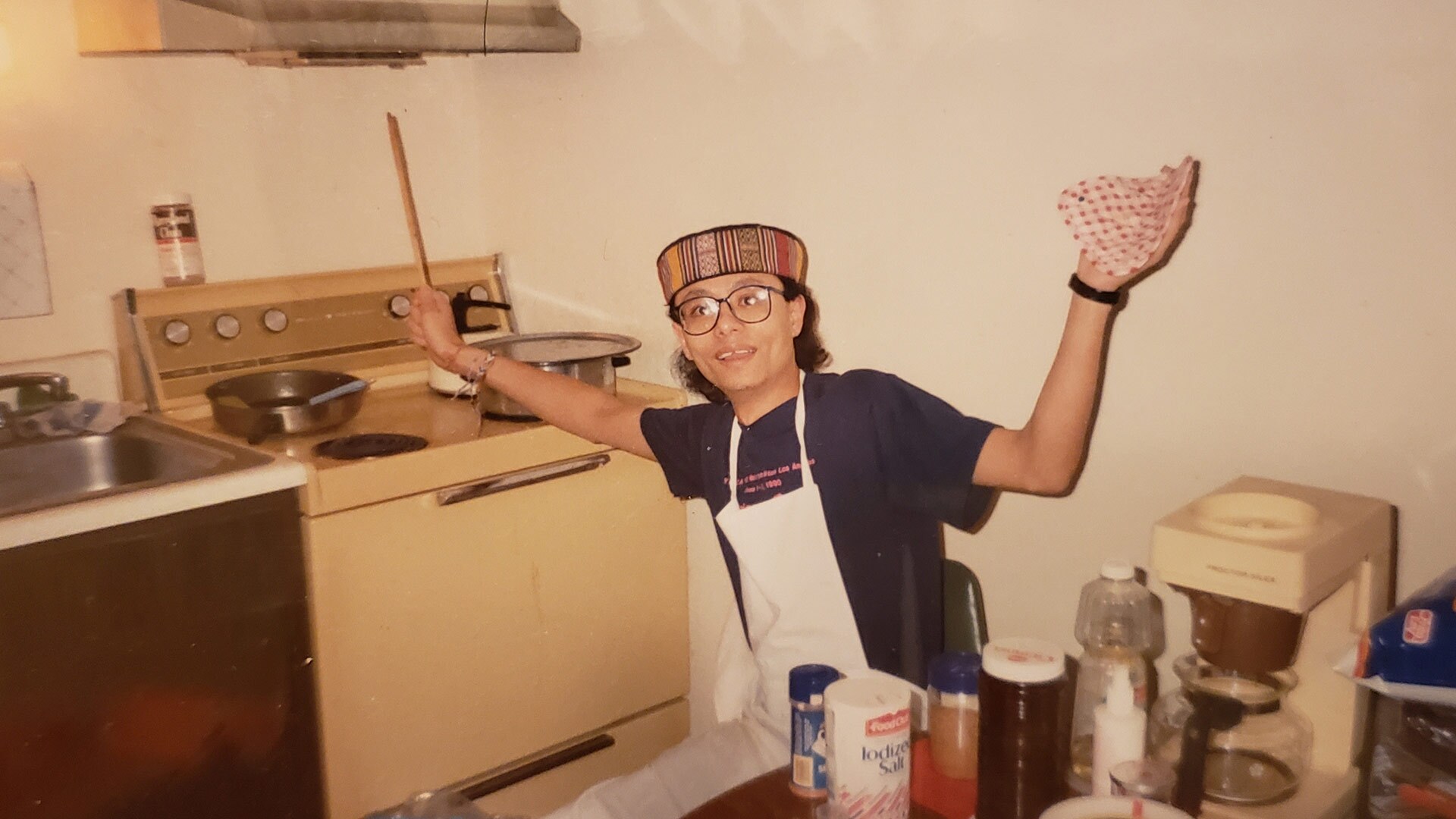 A man reaches for something on a stove next to him.