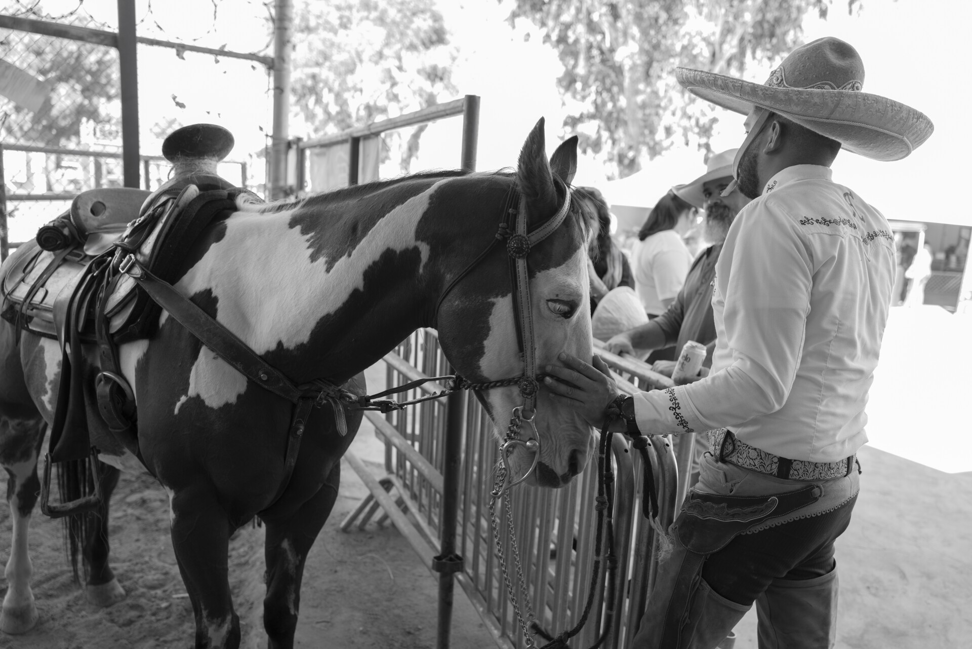 Un hombre vestido de vaquero acaricia a su caballo.