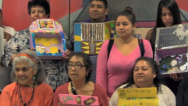 Master artist, Ofelia Esparza (bottom left) sits with participants from the alter making workshop exploring the need for affordable health care.