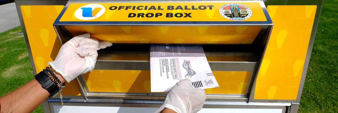 A woman wearing protective gloves posts her election ballot in an official ballot drop box on October 20, 2020 in Marina del Rey, California. | Amanda Edwards/Getty Images