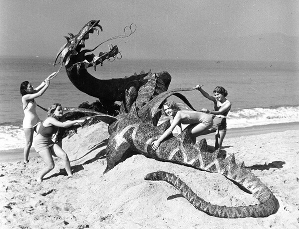 Women subdue a (fake) dragon on a Los Angeles beach, circa 1940. From the Los Angeles Area Chamber of Commerce Collection
