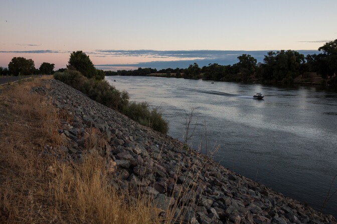 A boat floats down the Sacramento River next to a levee. | Photo by Andrew Burton/For The Washington Post via Getty Images