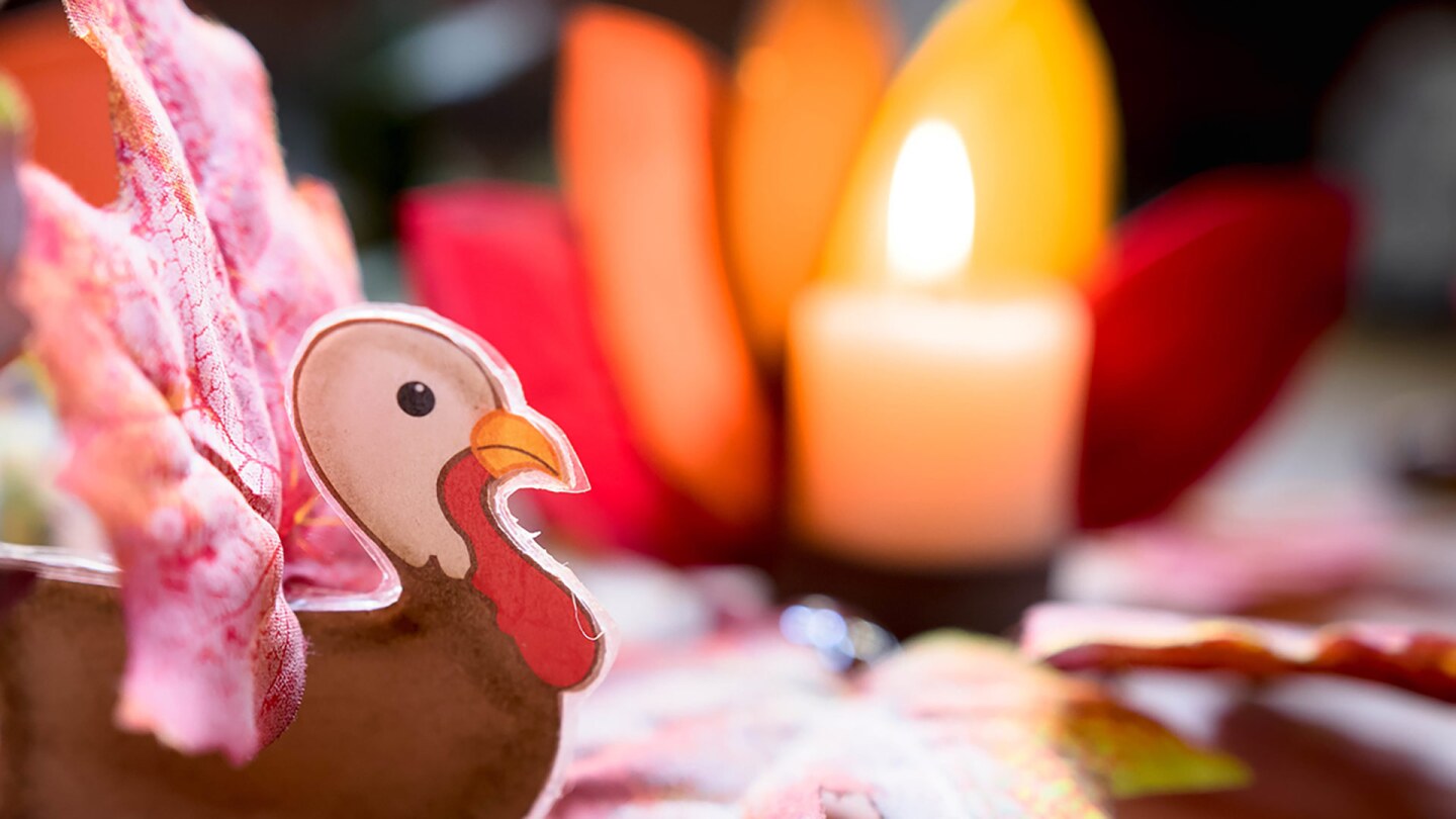 A small turkey craft in front of a candle