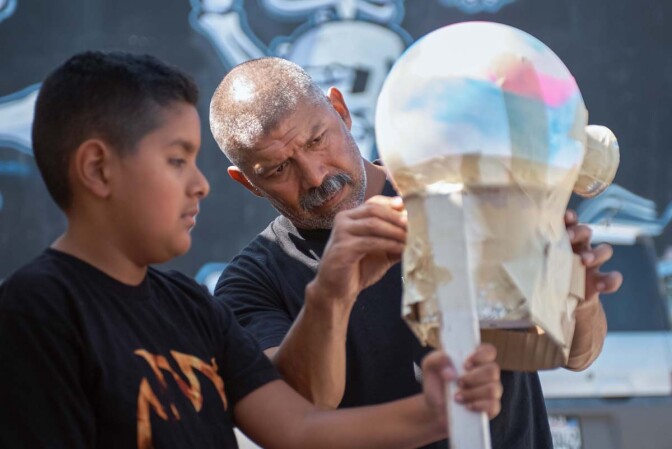A young boy and a man work on a sculpture at Self Help Graphics' Dia de los Muertos season of workshops, 2019. | Ken Marchionno
