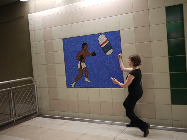 Artist Sara Wookey prompts tour participants to pose like their favorite sports portrait along a wall at the Civic Center station | Photo: George Villanueva