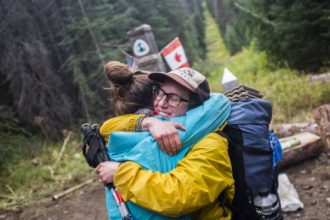 Two people hug after a long exhausting hike.