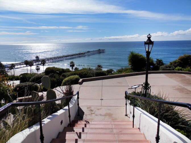 Outdoor stairs lead to a landing that looks out to a view of the ocean. 