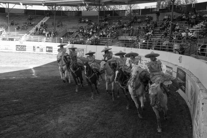 Mujeres vestidas con el atuendo tradicional de Charreada rodean la pluma circular de Pico Rivera.