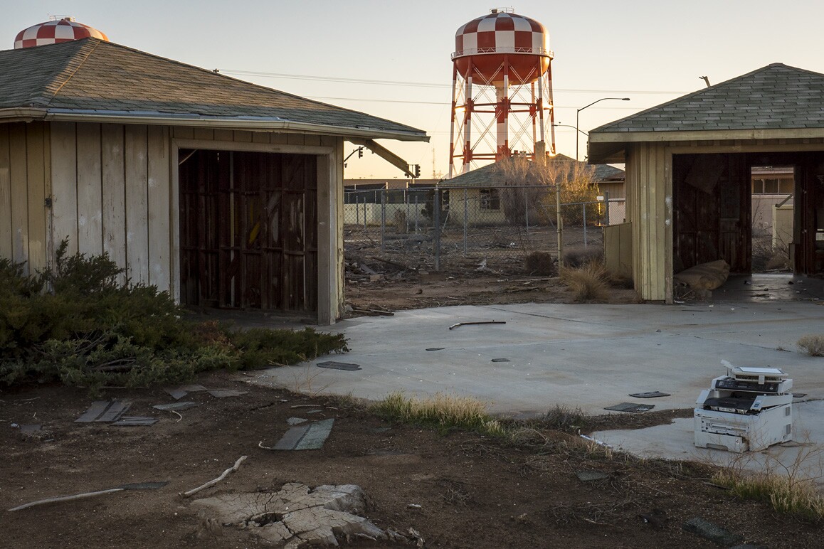 Empty garages of George Air Force Base's former housing with a water tower serving Victorville's Federal Correctional Complex in the distance. Photo: Kim Stringfellow.
