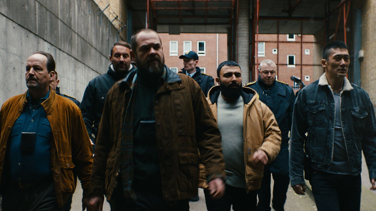 Group of men walk through industrial area. | Laust Trier Moerk / "Follow the Money"