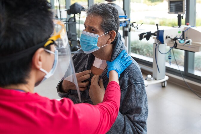 Speech pathologist Katherine Chan checks Vicente Perez Castro’s throat. He had a tracheotomy while in the hospital for COVID-19.