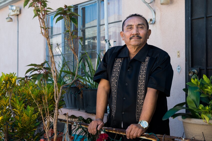 Pablo Ek Oxte stands at a railing surrounded by plants at his Los Angeles home.